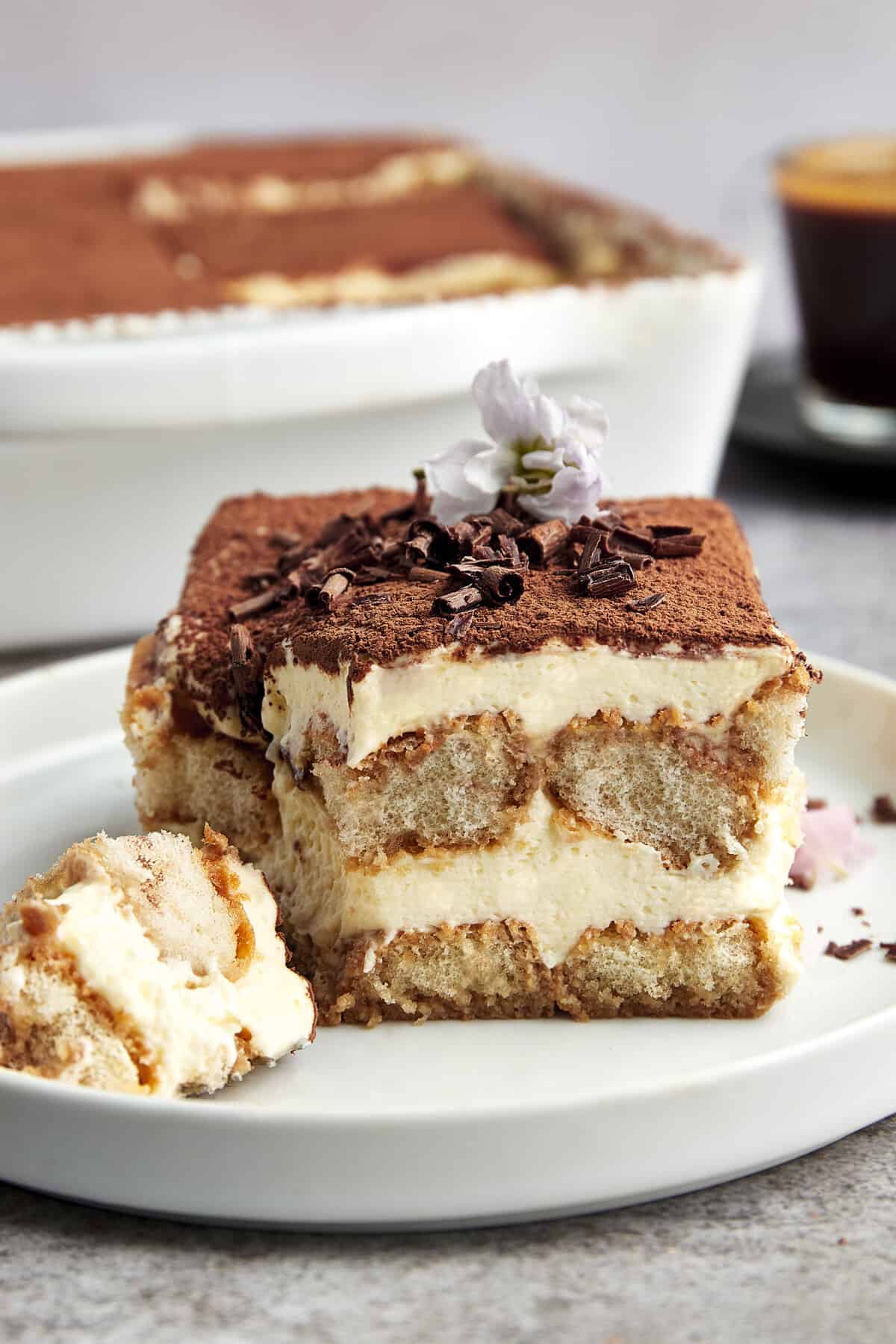 A slice of tiramisu on a plate with a fork holding a bite.