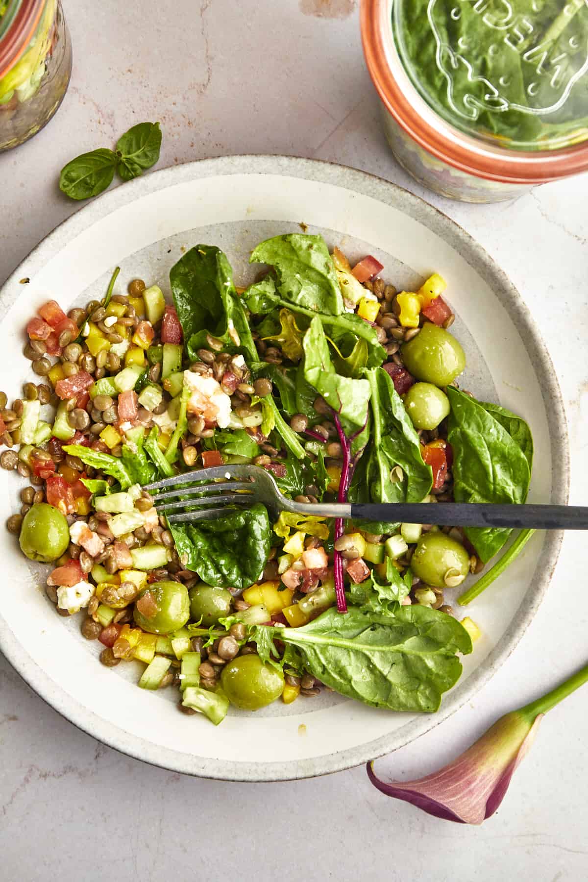 Overhead image of a bowl full of a mason jar salad with mango with a fork on top. 