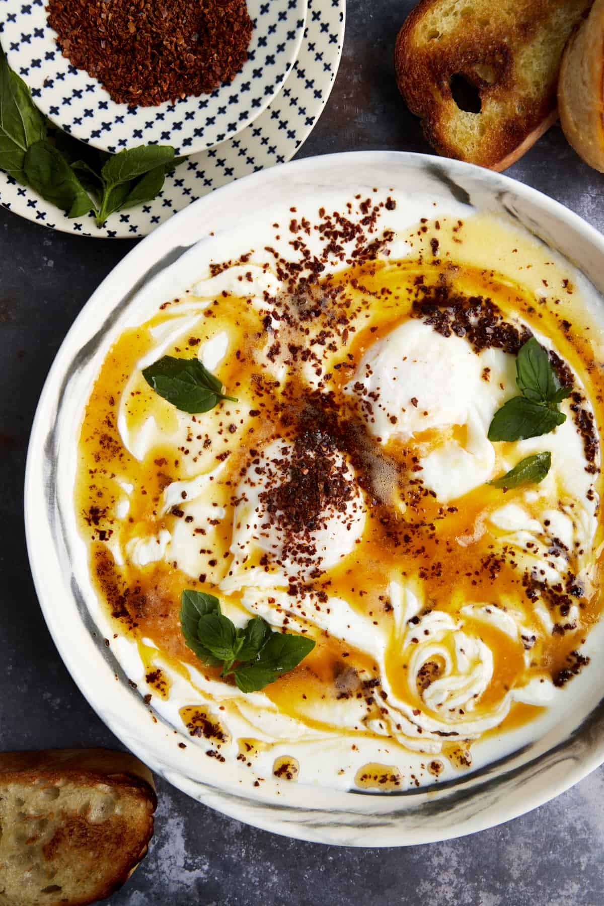 Overhead image of a bowl of Turkish Poached Eggs with Cottage Cheese topped with Aleppo pepper. 