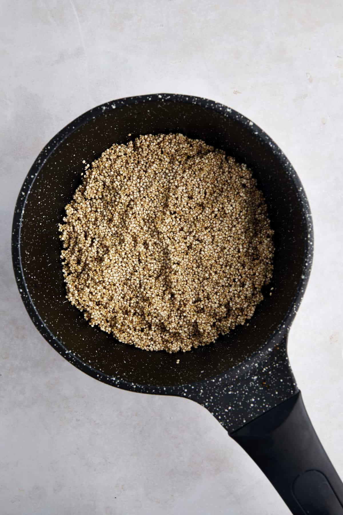 Overhead image of a pot of uncooked white quinoa. 