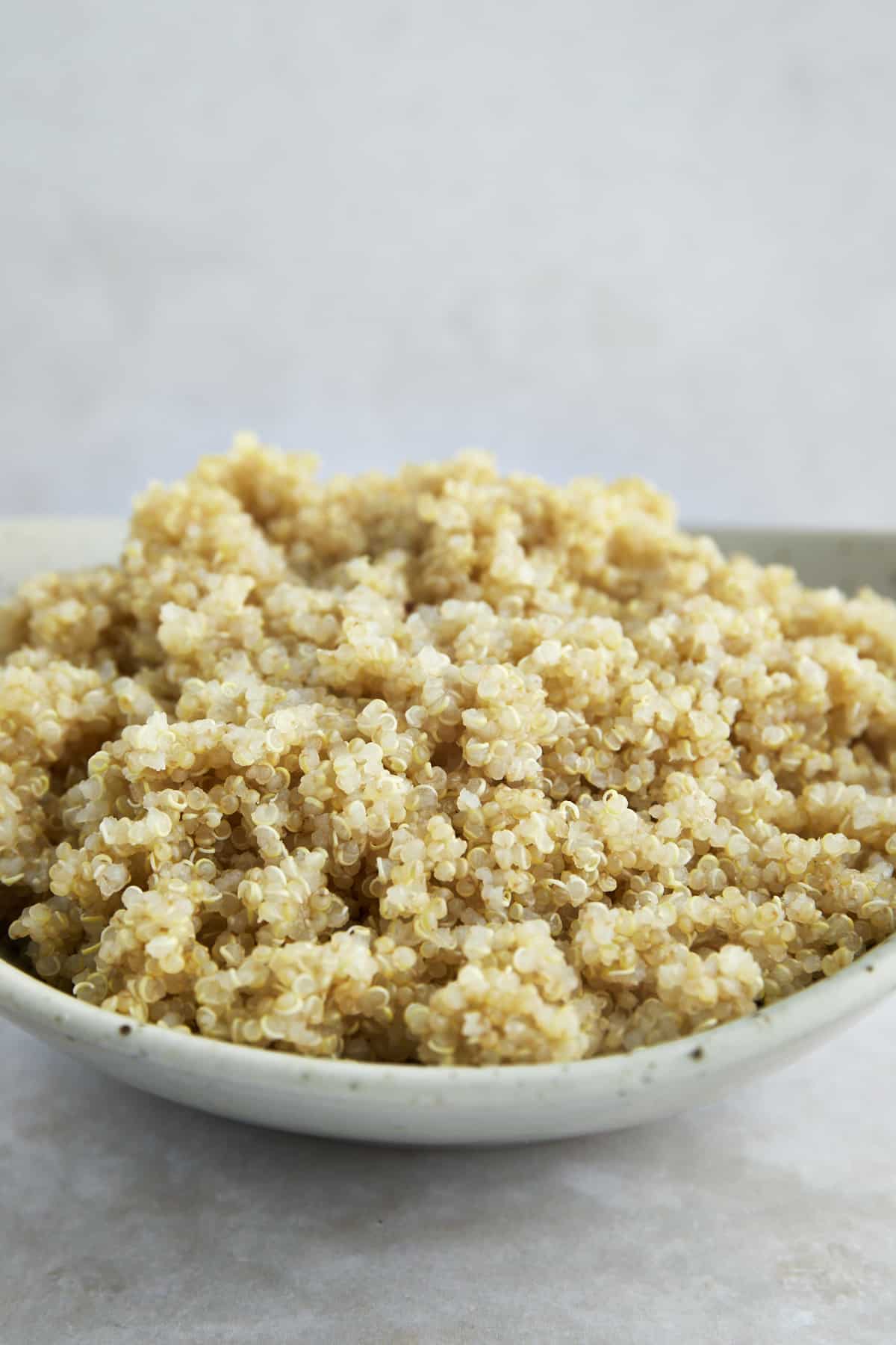 Side view of a bowl of fluffy cooked quinoa. 