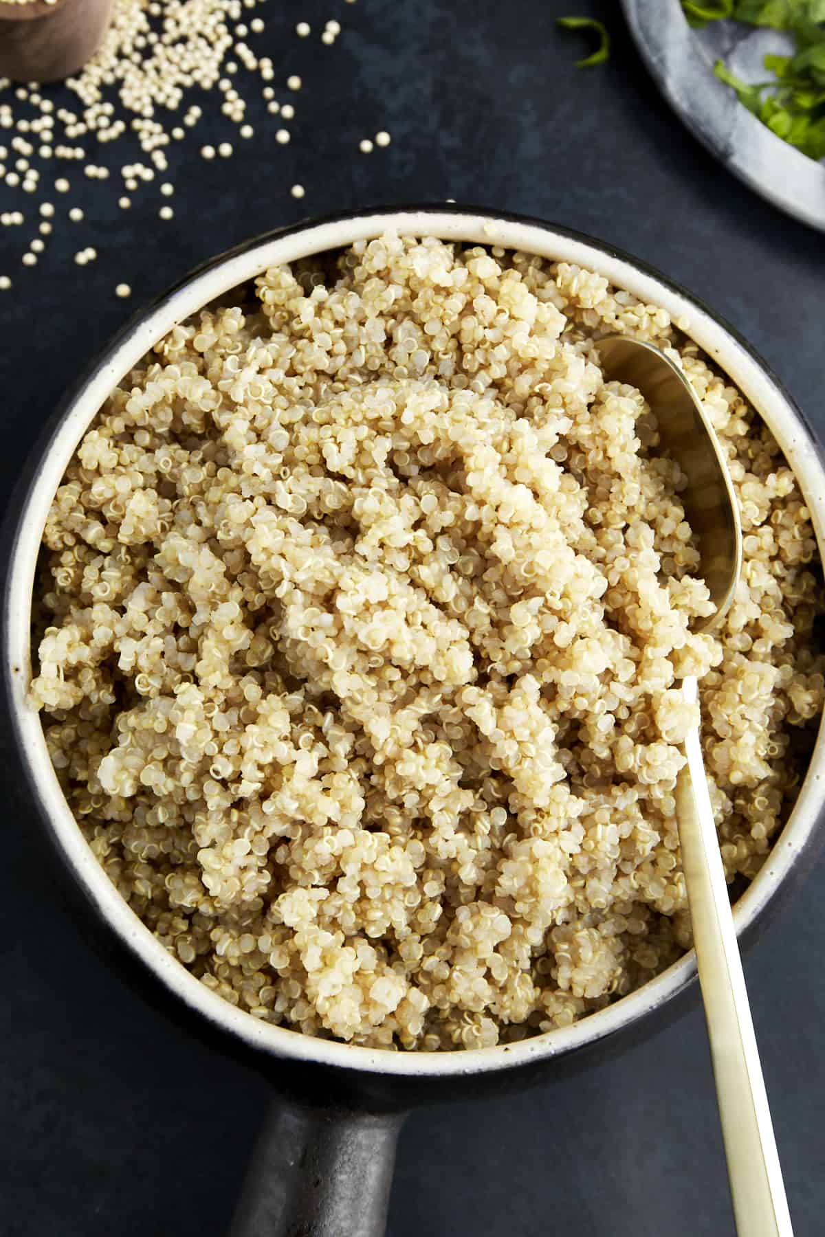 A bowl of cooked quinoa with a spoon sticking out. 