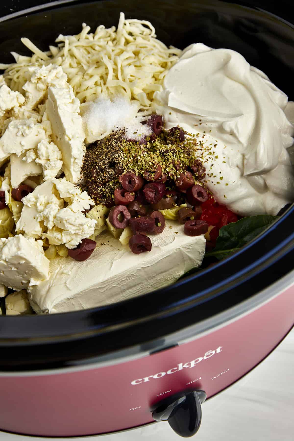 Ingredients for a warm spinach and artichoke dip recipe in a crockpot. 