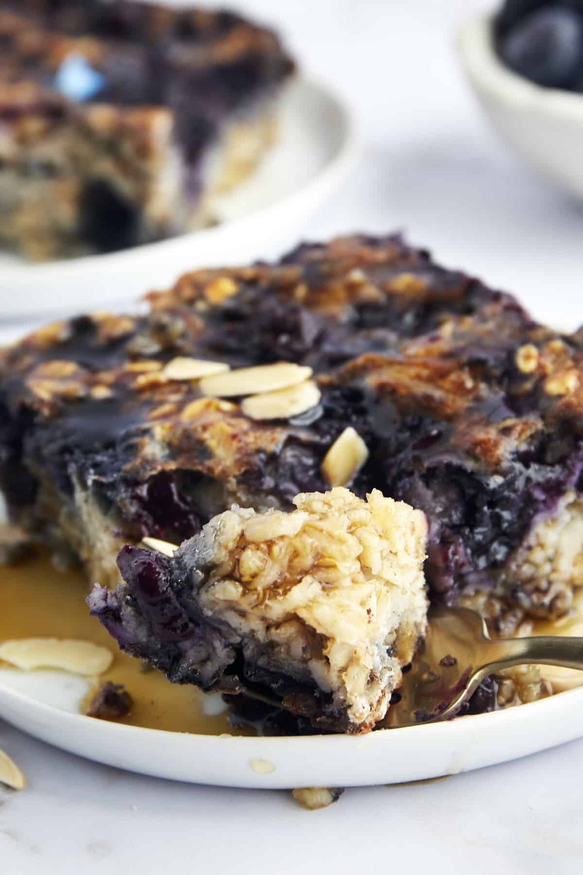 A plate of blueberry baked oats with a fork holding a bite. 
