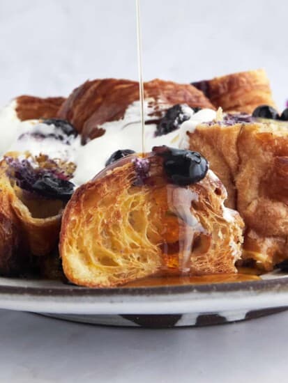 Maple syrup being poured on top of croissant blueberry French toast.