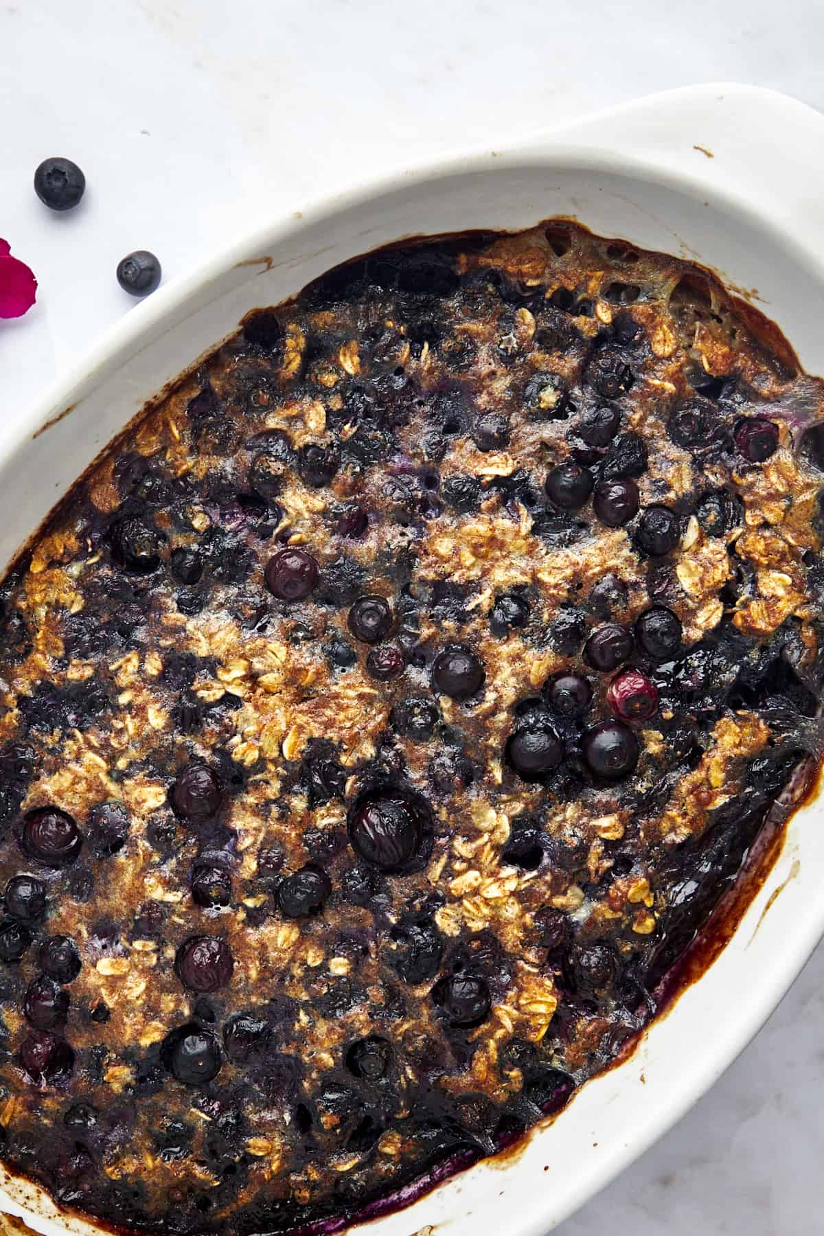An oval baking dish full of blueberry baked oatmeal.