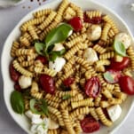 A bowl of caprese pasta salad topped with fresh basil.