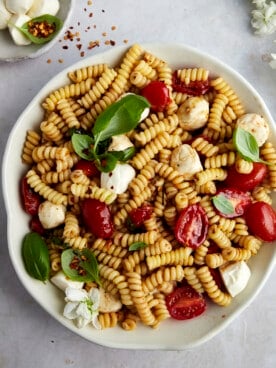 A bowl of caprese pasta salad topped with fresh basil.