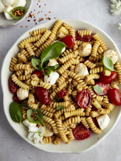 A bowl of caprese pasta salad topped with fresh basil.
