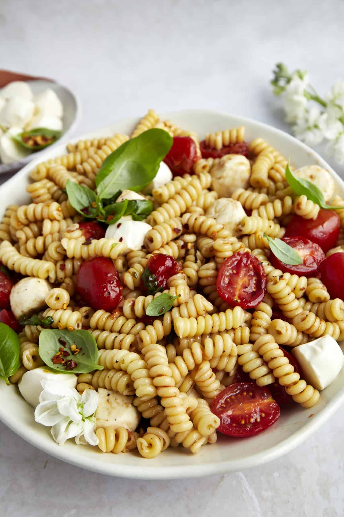 A bowl of caprese pasta salad topped with balsamic glaze.