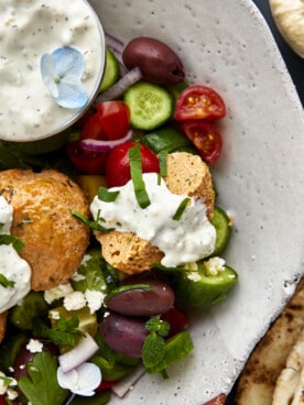 A bowl of chicken shawarma meatballs with veggies and tzatziki.