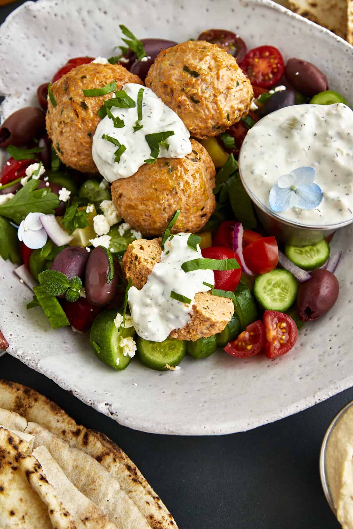 A bowl of chicken shawarma meatballs with veggies and tzatziki. 