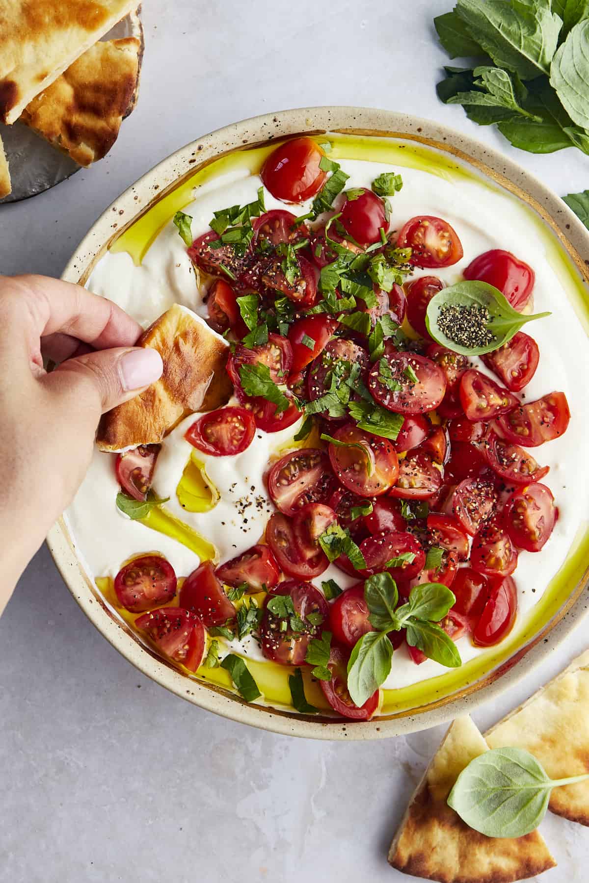 Marinated tomatoes over whipped feta with pita bread being dipped in.