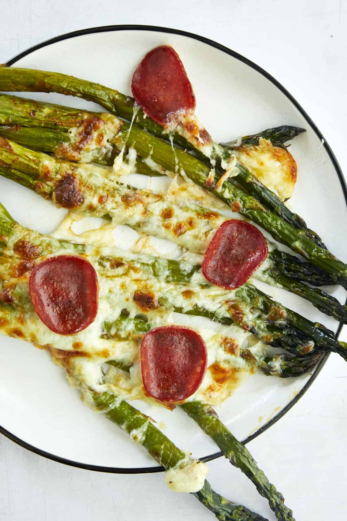 A serving of pizza-flavored oven baked asparagus on a plate. 