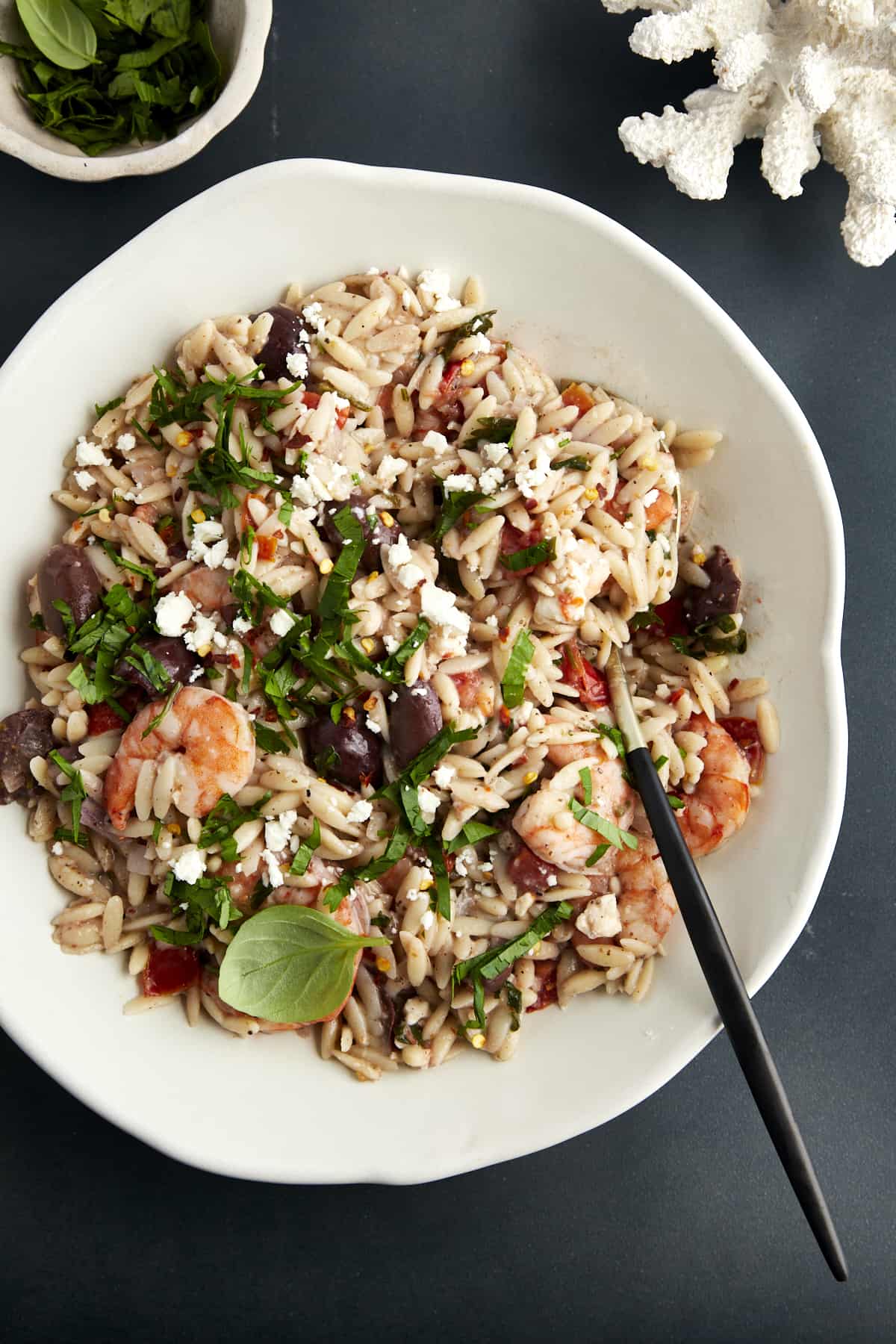 A bowl of shrimp orzo bake with a spoon sticking out. 