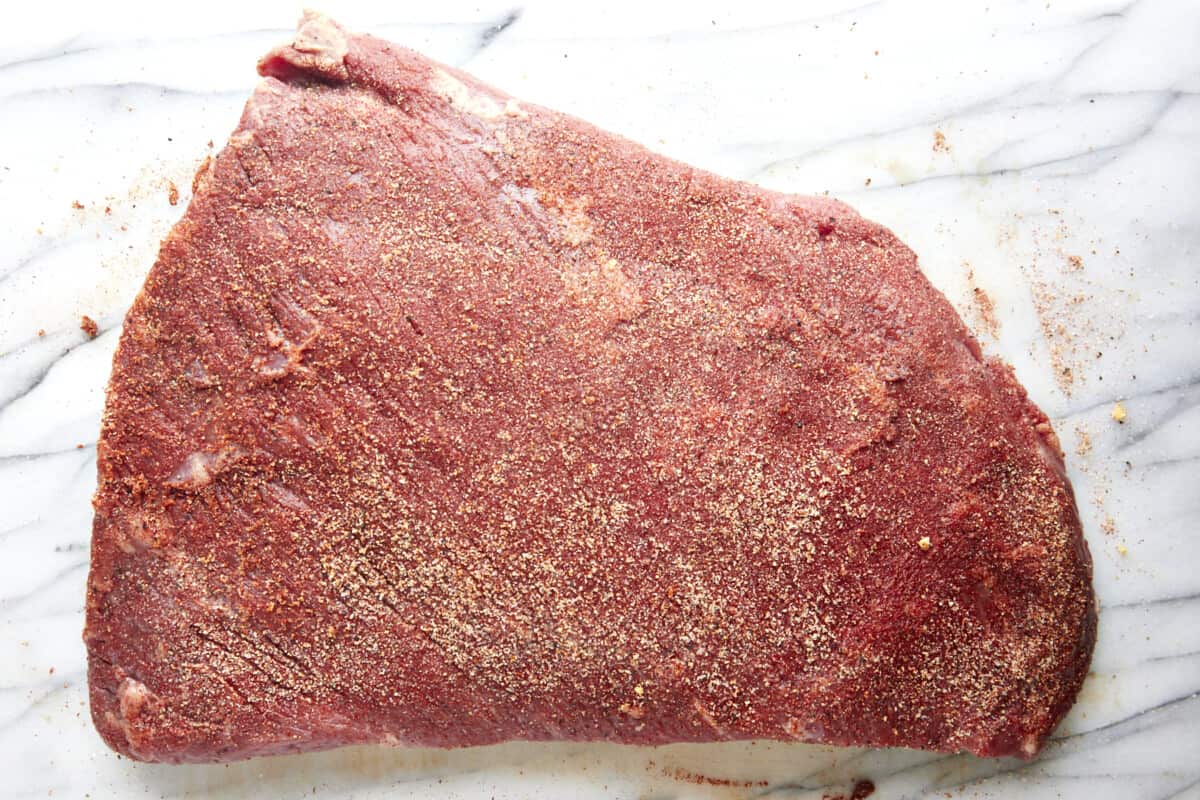 A raw, seasoned three pound beef brisket. 