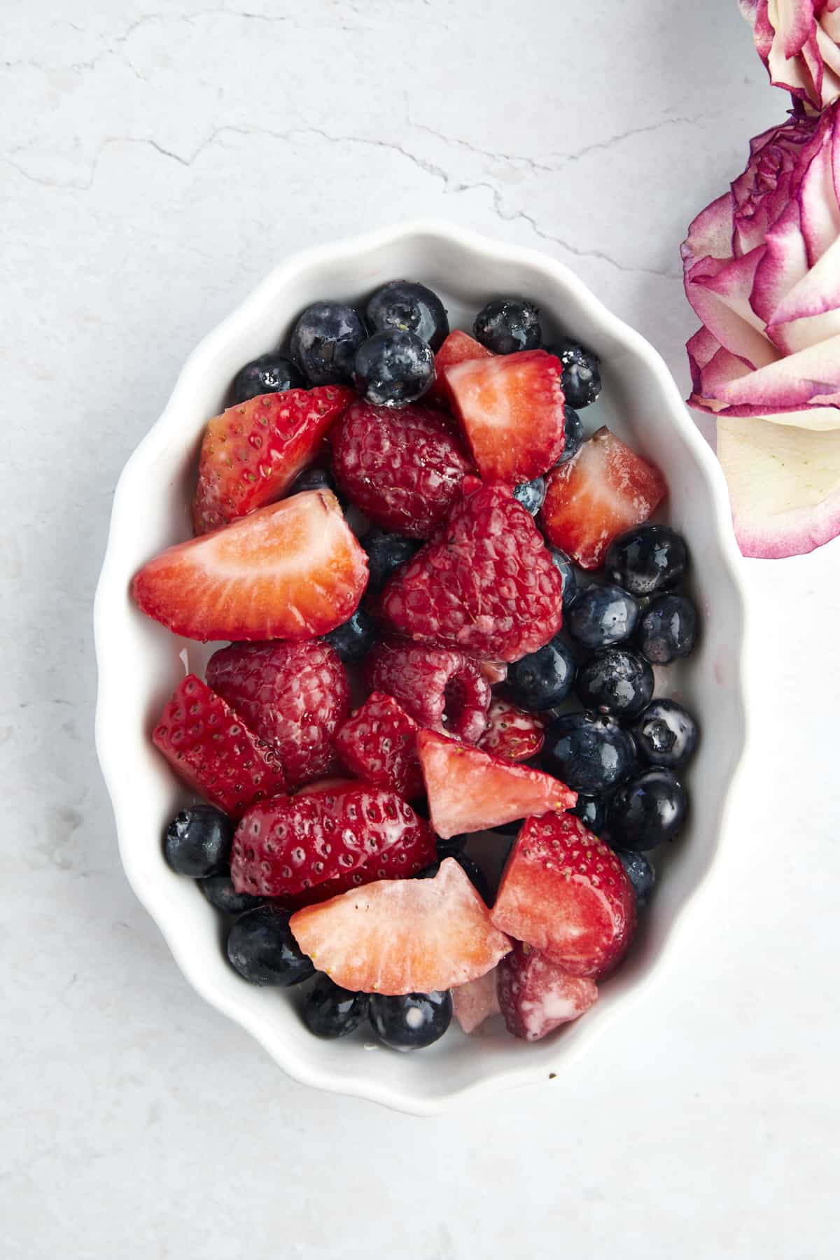 Raspberries, strawberries, and blueberries in an oval baking dish. 