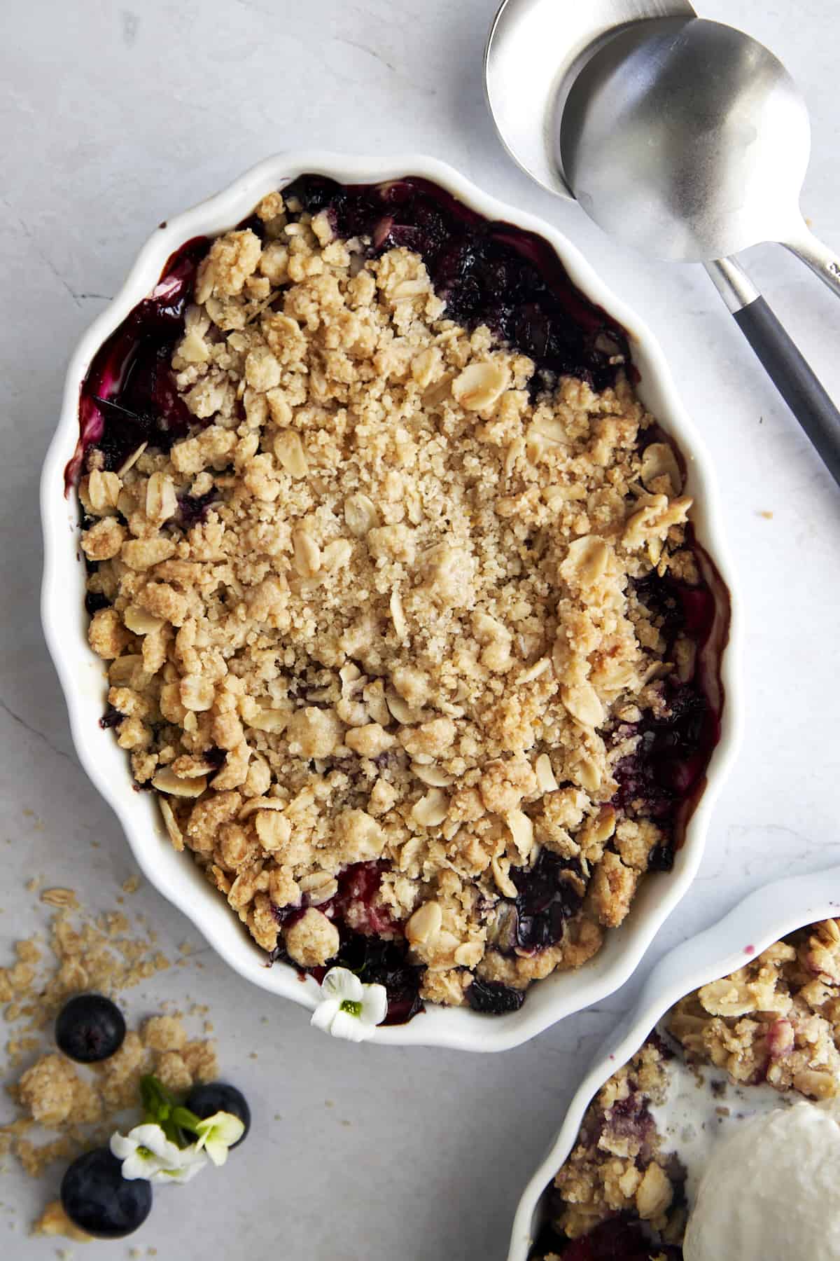 Overhead image of a white oval baking dish full of baked mixed berry crisp. 