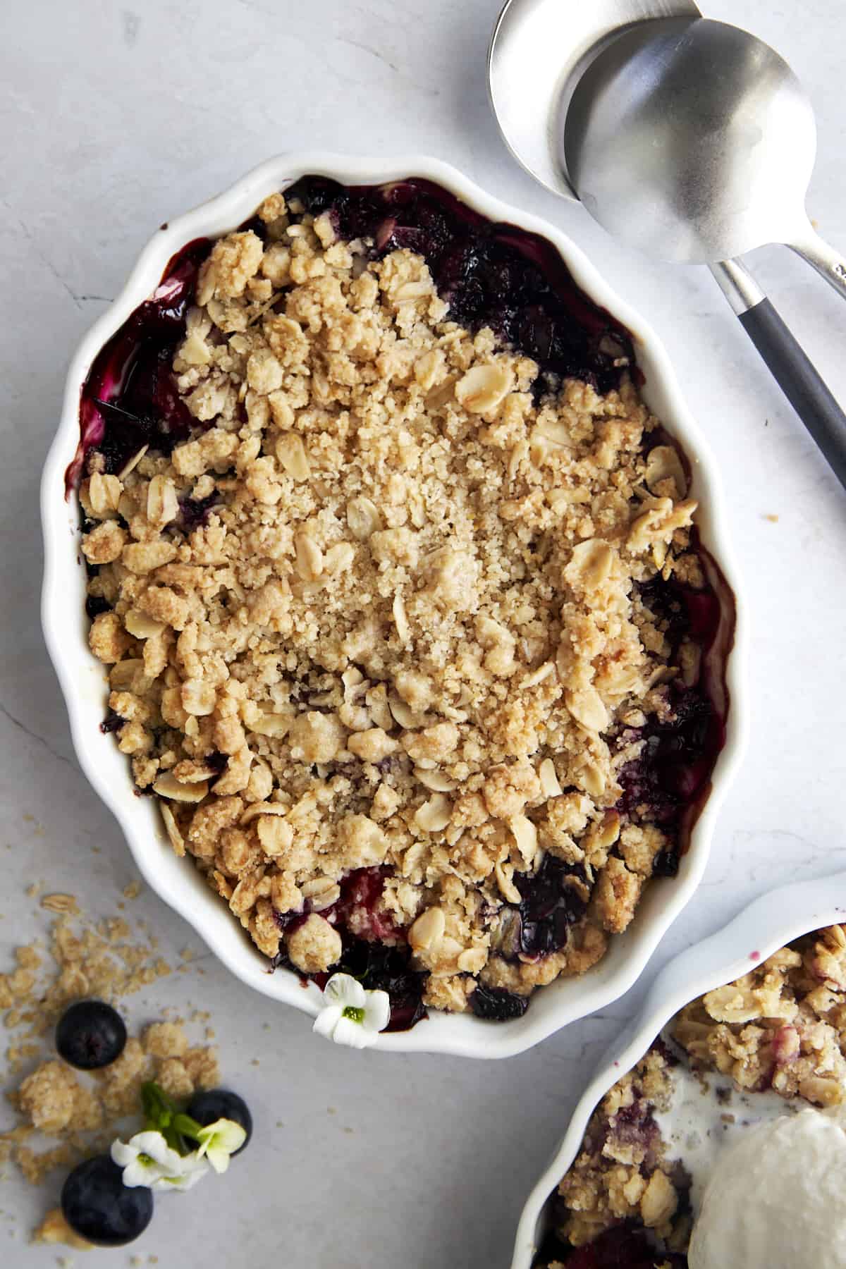 Overhead image of a white oval baking dish full of baked mixed berry crisp.
