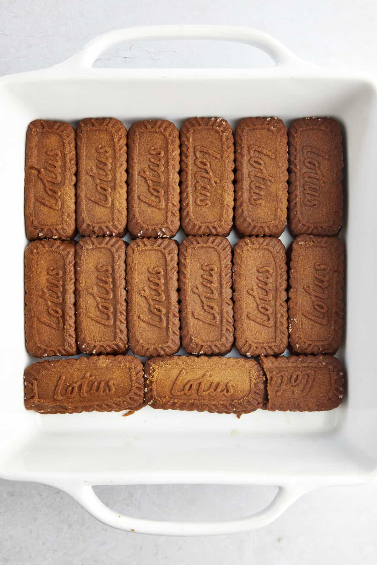 Espresso-soaked Biscoff cookies layered in the bottom of a baking dish. 