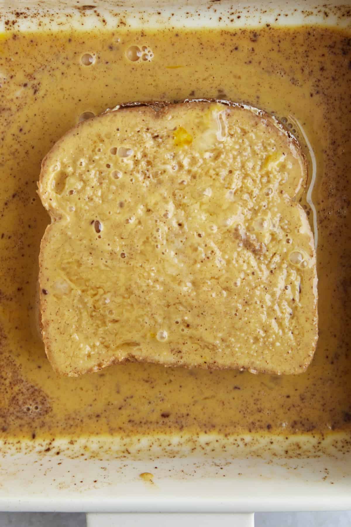 Cream cheese stuffed bread being dipped in an egg wash. 