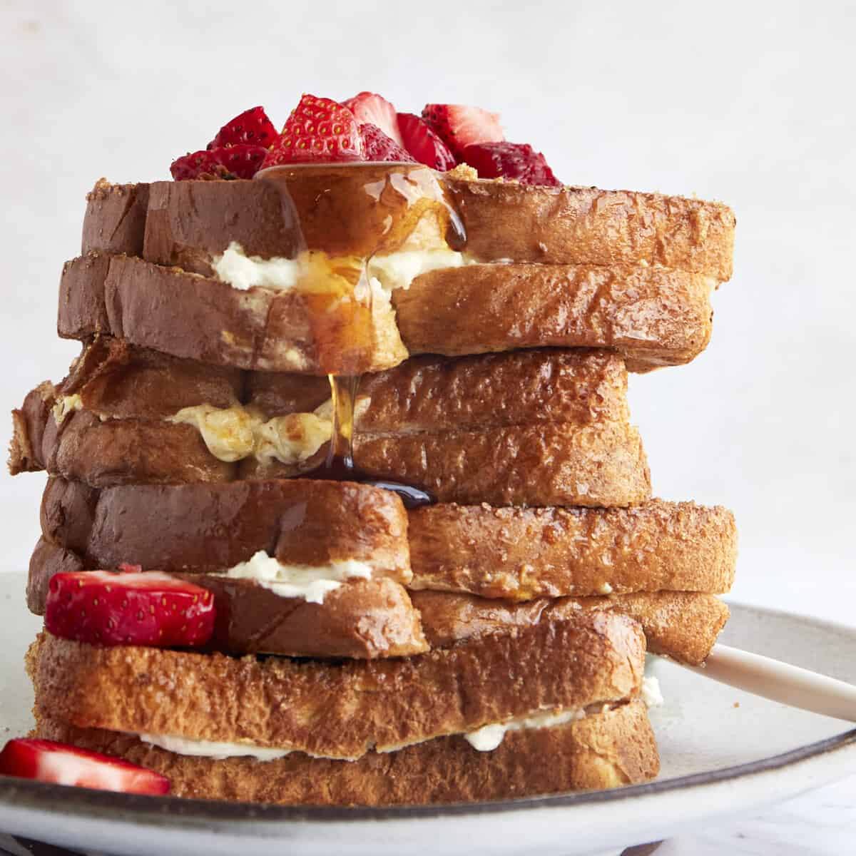 Air fryer french toast sandwiches on a plate topped with berries.