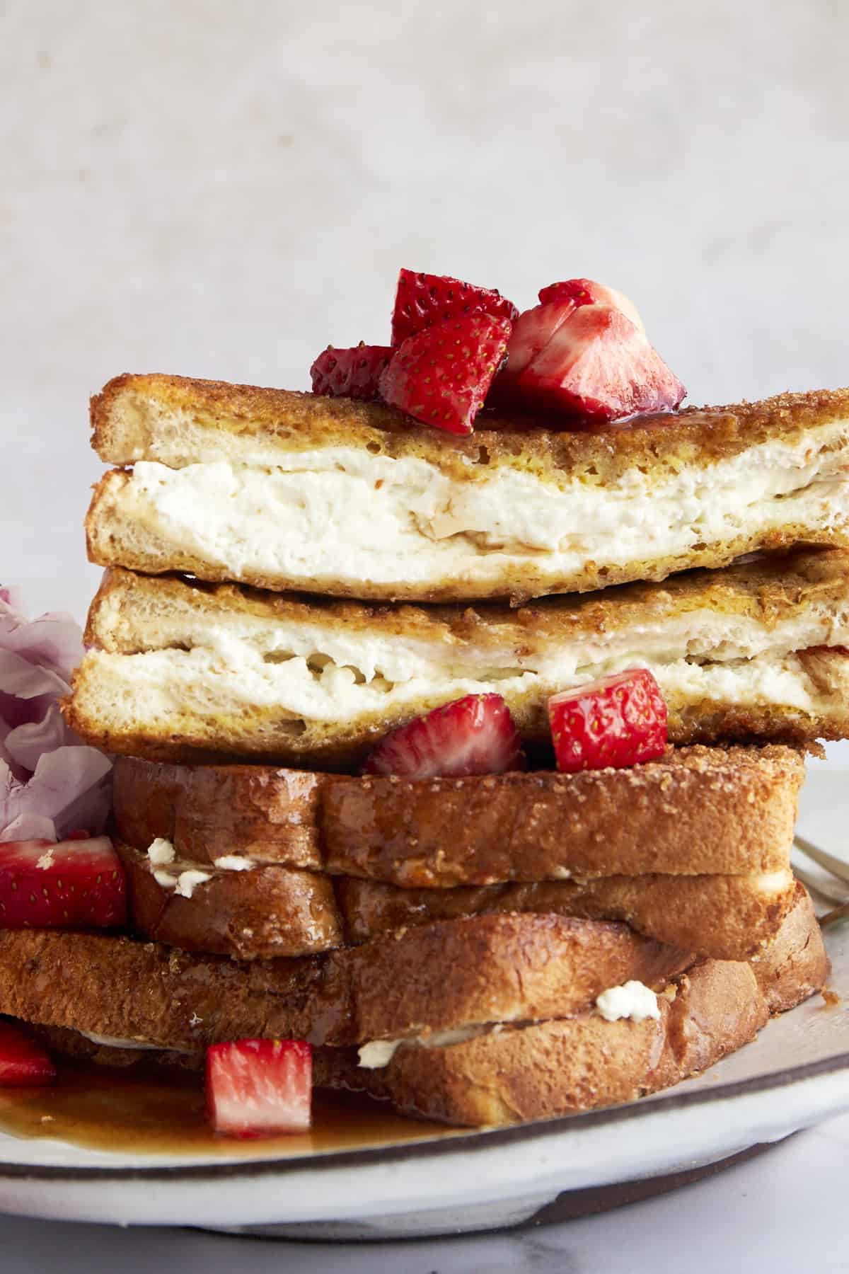 Stacked air fryer french toast with the top piece sliced in half showing the cream cheese center. 