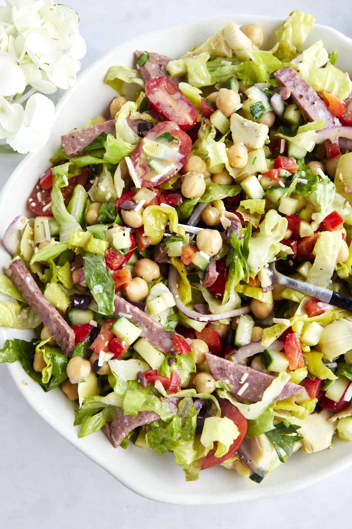 A fork in a bowl of dressed Italian chopped salad. 
