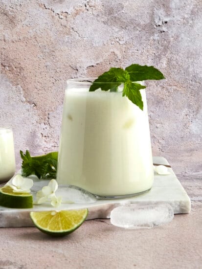 A glass of Egyptian mint lemonade topped with a fresh mint leaf.