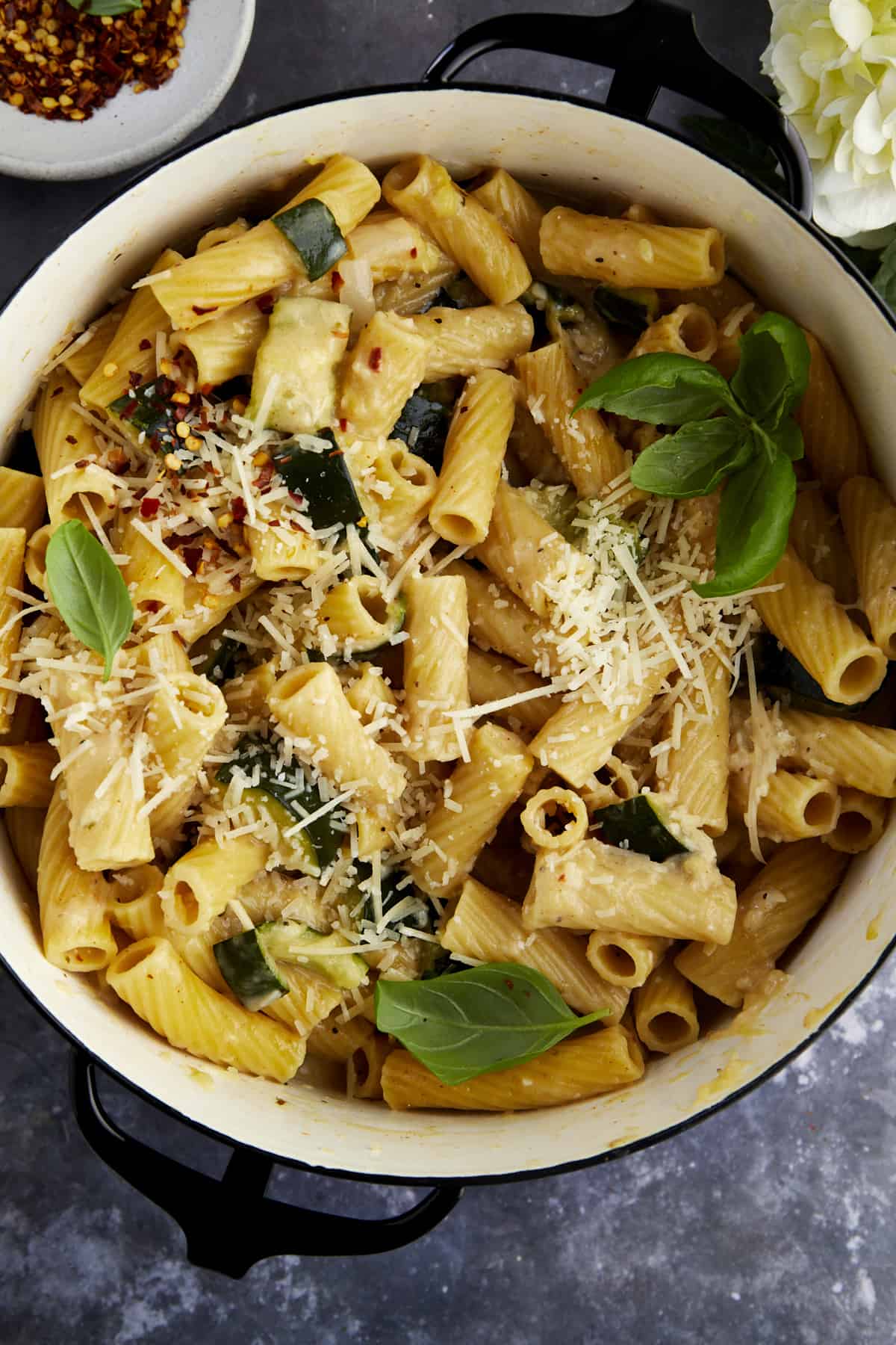 Overhead image of a pot of pasta with zucchini topped with extra Parmesan. 