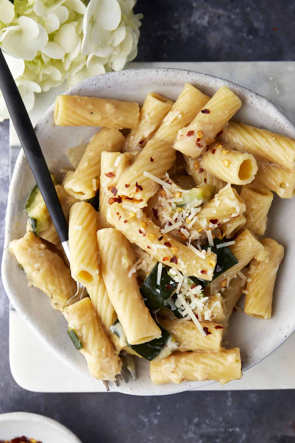 A serving of one-pot pasta with zucchini on a plate with a fork.