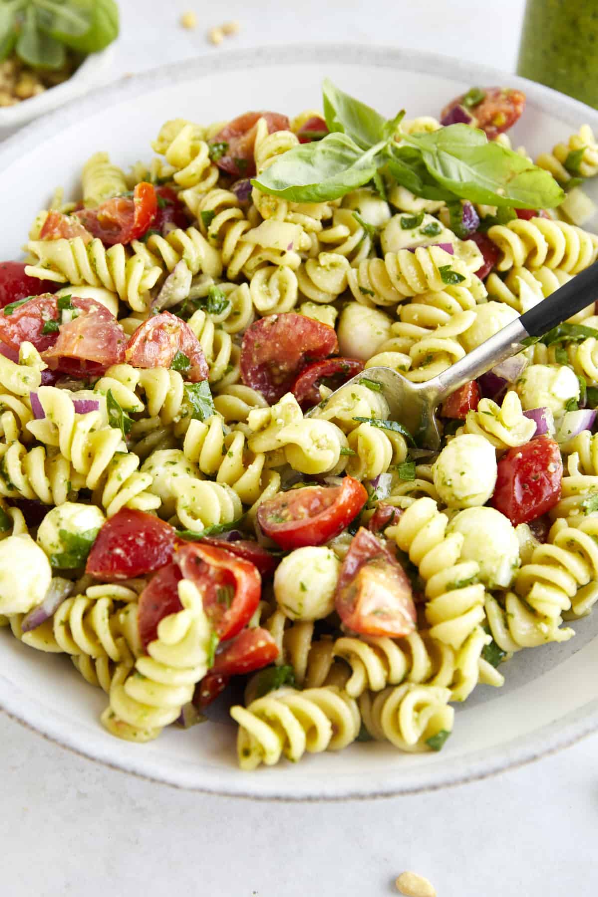 A fork spearing a bite of pasta salad with pesto. 