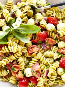 A bowl of pasta salad with pesto topped with fresh basil.
