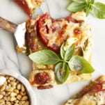 A slice of tomato pesto puff pastry topped with fresh basil.