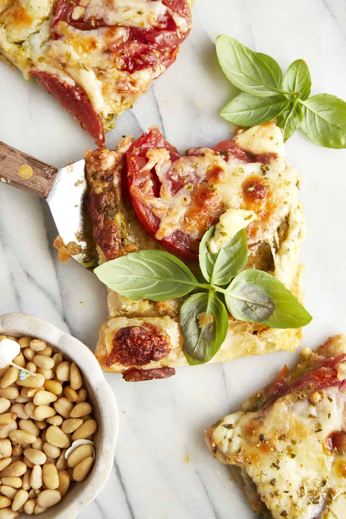 A piece of tomato pesto puff pastry under a serving utensil. 