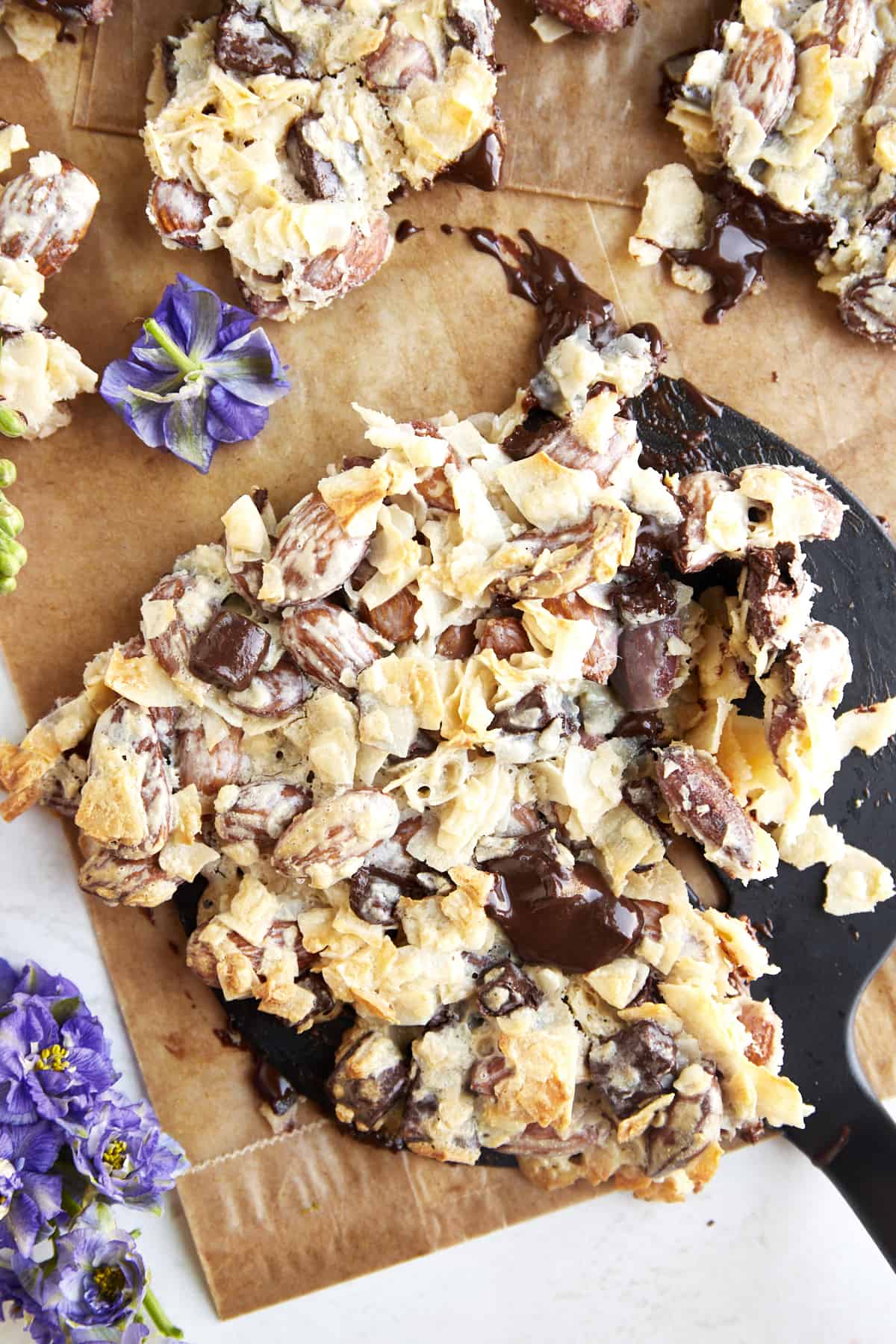 A spatula scooping up a piece of coconut chocolate almond bark. 