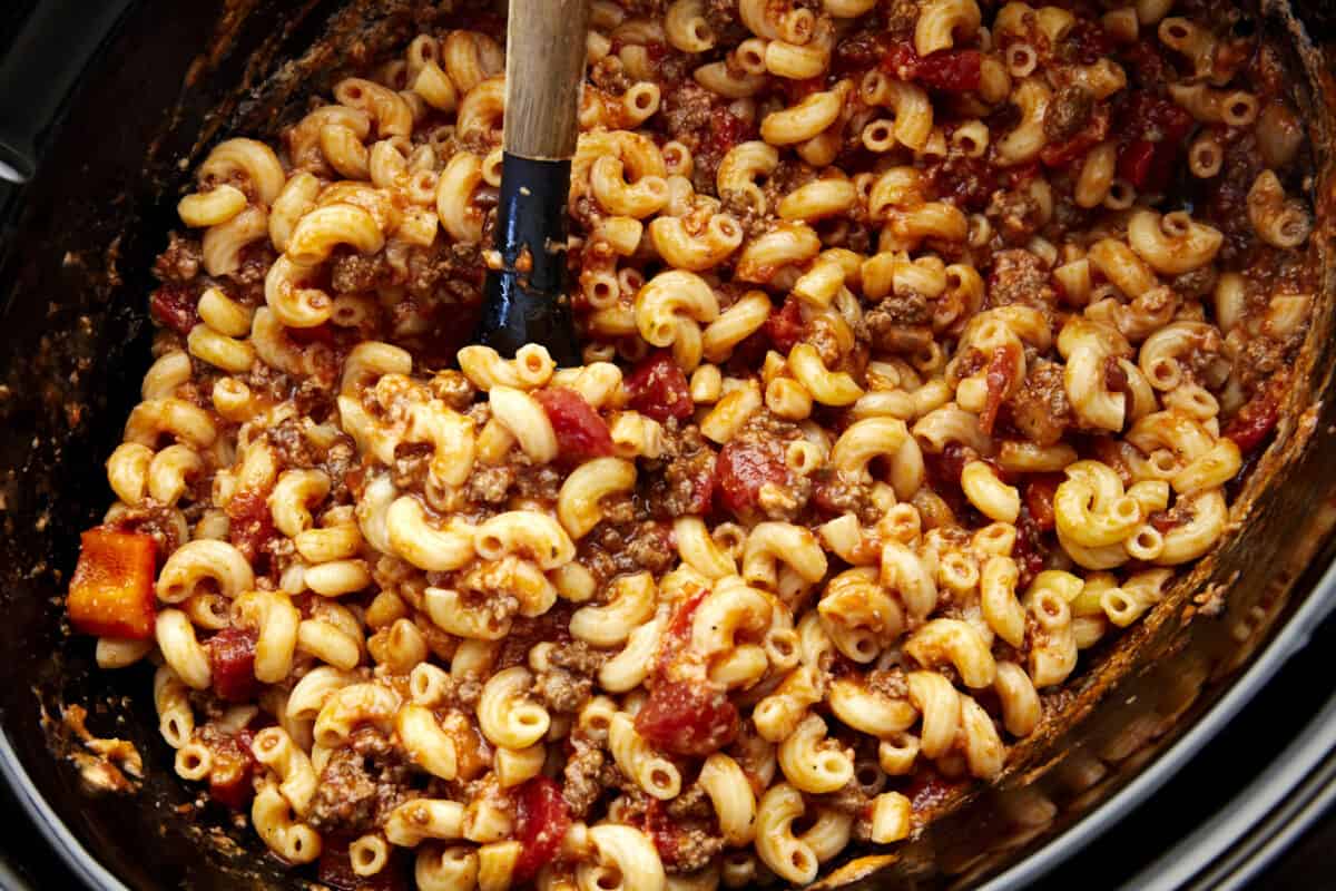 A slow cooker full of ground beef pasta being stored. 