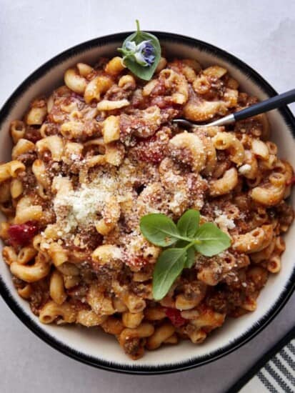 A bowl of ground beef pasta with a spoon sticking out.