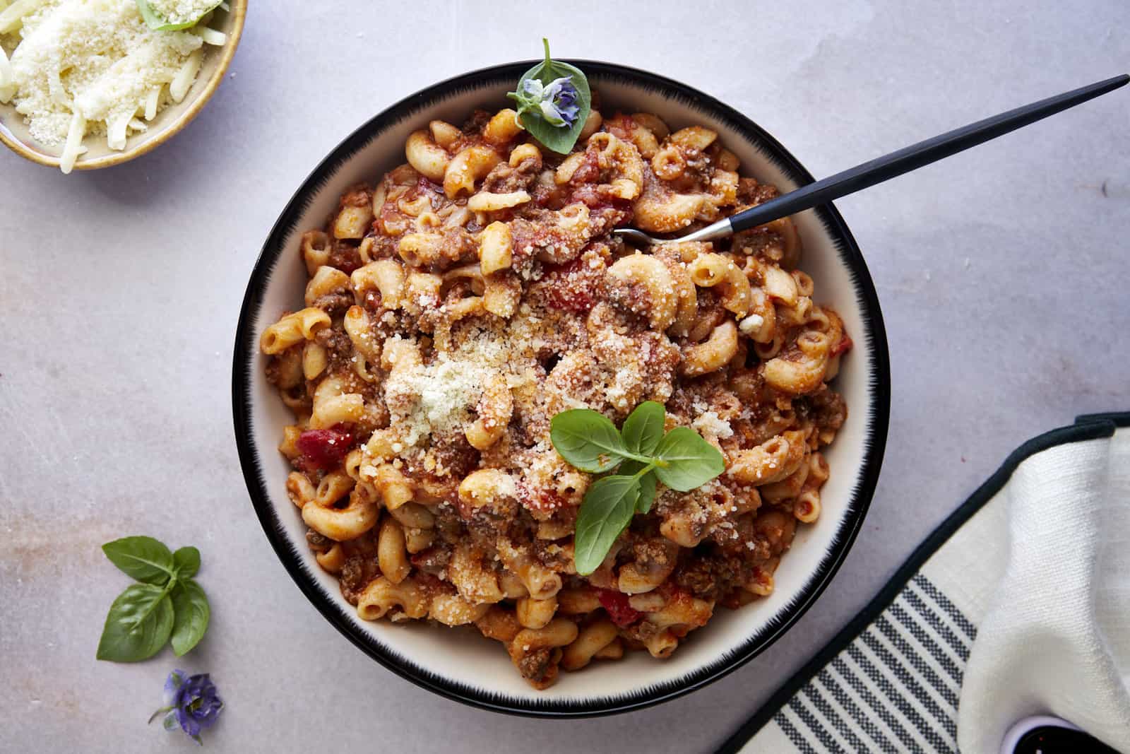 A bowl of ground beef pasta with a spoon sticking out.