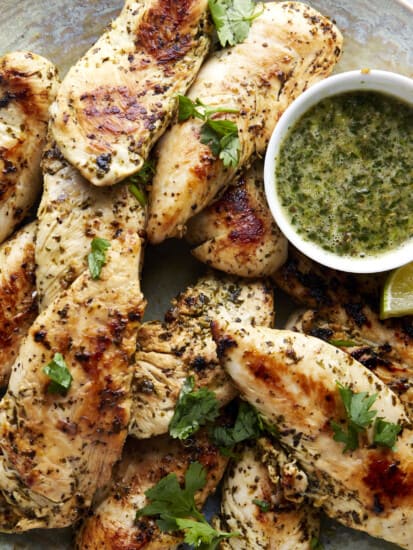 A basket of lime chicken tenders with a side of sauce.