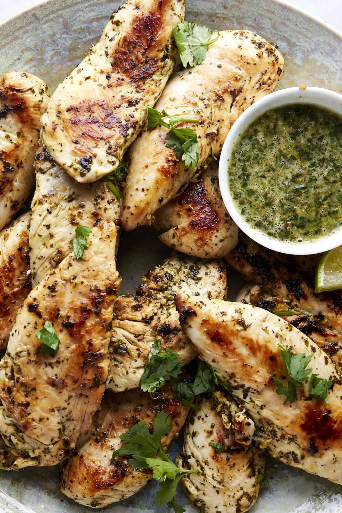 A bowl of air fryer lime chicken tenders with a side of lime sauce. 