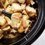A spoon scooping up a serving of crockpot French toast casserole.