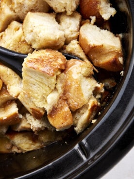 A spoon scooping up a serving of crockpot French toast casserole.