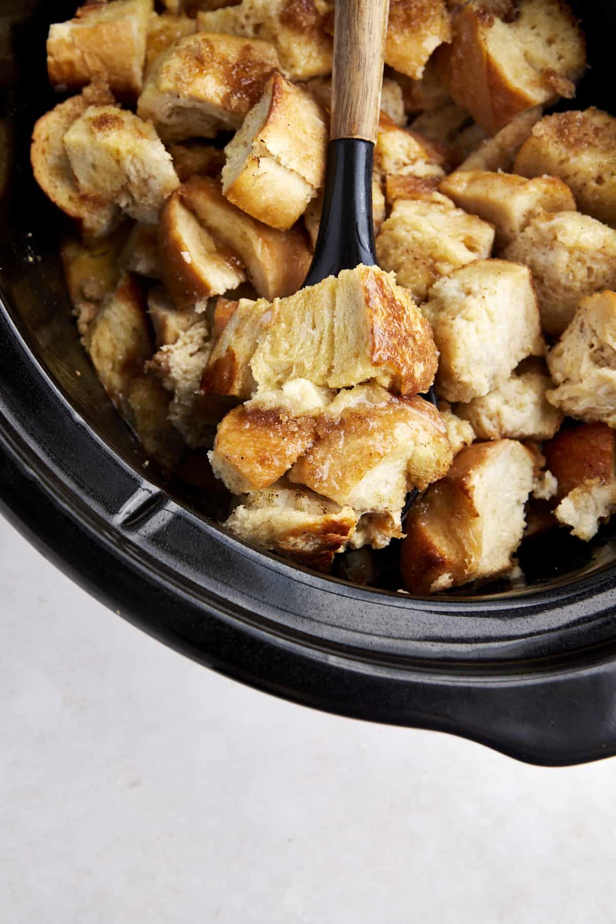A bite of crockpot French toast casserole being lifted with a spoon.
