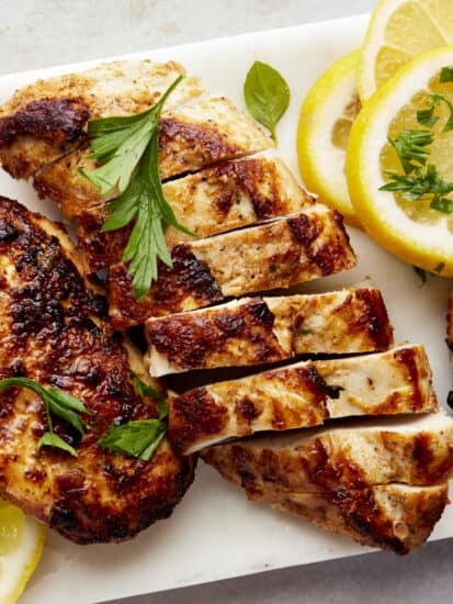 Sliced Greek lemon chicken on a cutting board.