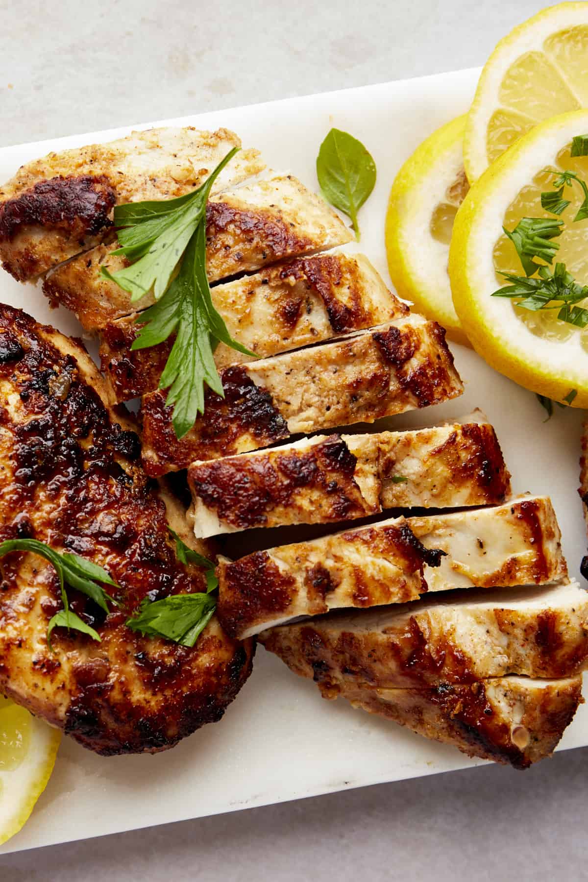 Sliced Greek lemon chicken on a cutting board.