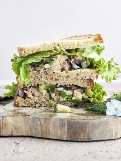 Two halves of a Mediterranean tuna salad sandwich stacked on top of each other.
