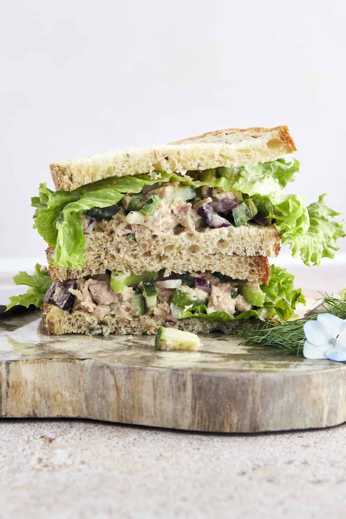 Two halves of a Mediterranean tuna salad sandwich stacked on top of each other. 