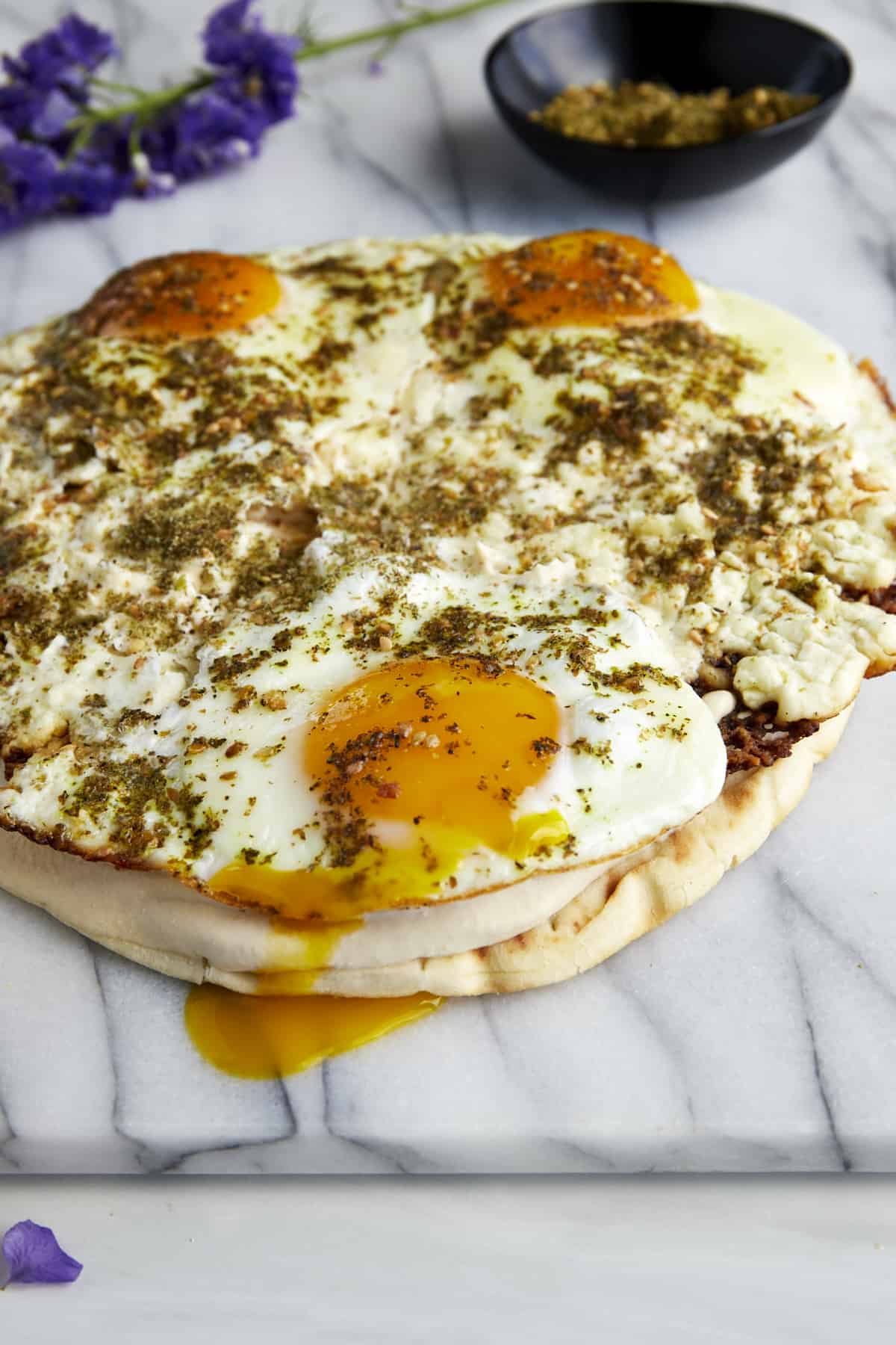 Fried feta eggs topped with za'atar and red pepper flakes on pita with hummus.