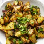 A plate of air fryer golden potatoes with harissa sauce topped with parsley.